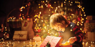 Christmas Child Open Present Gift, Happy Baby Boy looking to Magic Light in Box, Kid sitting front of Xmas Tree