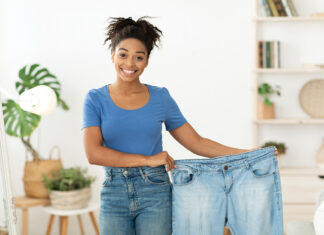 Happy Slim Black Girl Showing Old Jeans Standing At Home