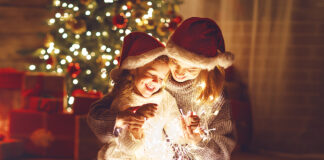 Merry Christmas! mother and child daughter with a glowing Christmas garland near tree