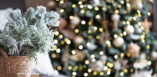 Beautiful holiday card. The concept of a happy new year and Christmas 2024. Christmas trees and a home sign on a wooden table in a cozy living room.