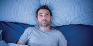 Anxious man trying to sleep but suffering insomnia