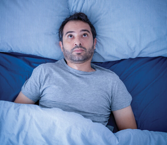 Anxious man trying to sleep but suffering insomnia