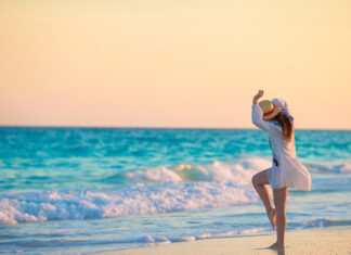 Young happy woman in swimsuit on white beach
