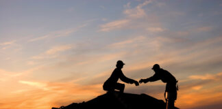 Two roofers working late on a roof top