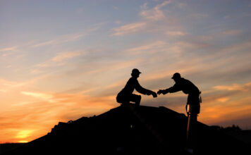 Two roofers working late on a roof top