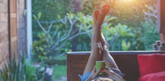 Girl enjoying early morning coffee on the garden sofa.