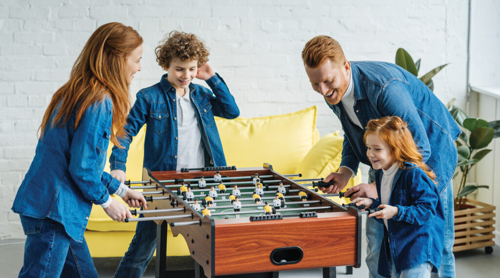 Happy family having fun while playing foosball