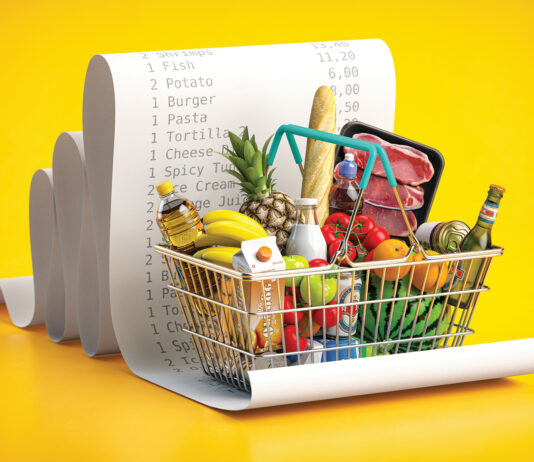 Shopping basket with foods on receipt. Grocery expenses budget, inflation and consumerism concept.