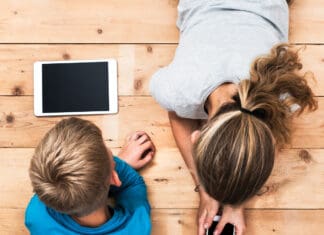 Change is Me, Change is We Top view image of two kids lying on the floor and playing with tablet and smartphone watching movie or gaming.