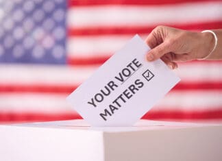 A Message from the Supervisor of Elections Hand Placing Ballot in Box With American Flag