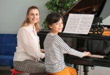 Private music teacher giving piano lessons to little boy