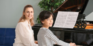 Private music teacher giving piano lessons to little boy