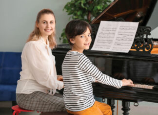 Private music teacher giving piano lessons to little boy