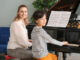 Private music teacher giving piano lessons to little boy