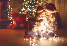 Merry Christmas! mother and child daughter with glowing garland near tree