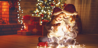 Merry Christmas! mother and child daughter with glowing garland near tree