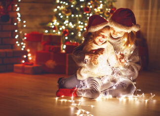 Merry Christmas! mother and child daughter with glowing garland near tree