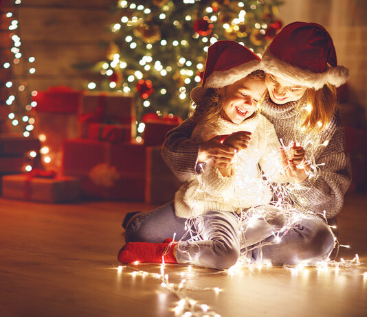 Merry Christmas! mother and child daughter with glowing garland near tree