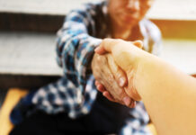 Close-up handshake for help homeless man on walking street in the capital city.