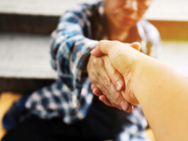 Close-up handshake for help homeless man on walking street in the capital city.