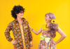 Asian hippie couple dress in 80s colorful vintage fashion with retro clothing while dancing together isolated on yellow background for fancy outfit party and pop culture