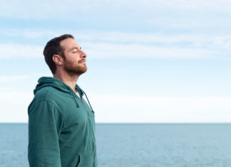 Relaxed man breathing fresh air with the sea at the background.