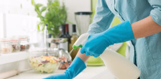 Woman cleaning and polishing the kitchen worktop with a spray detergent, housekeeping and hygiene concept